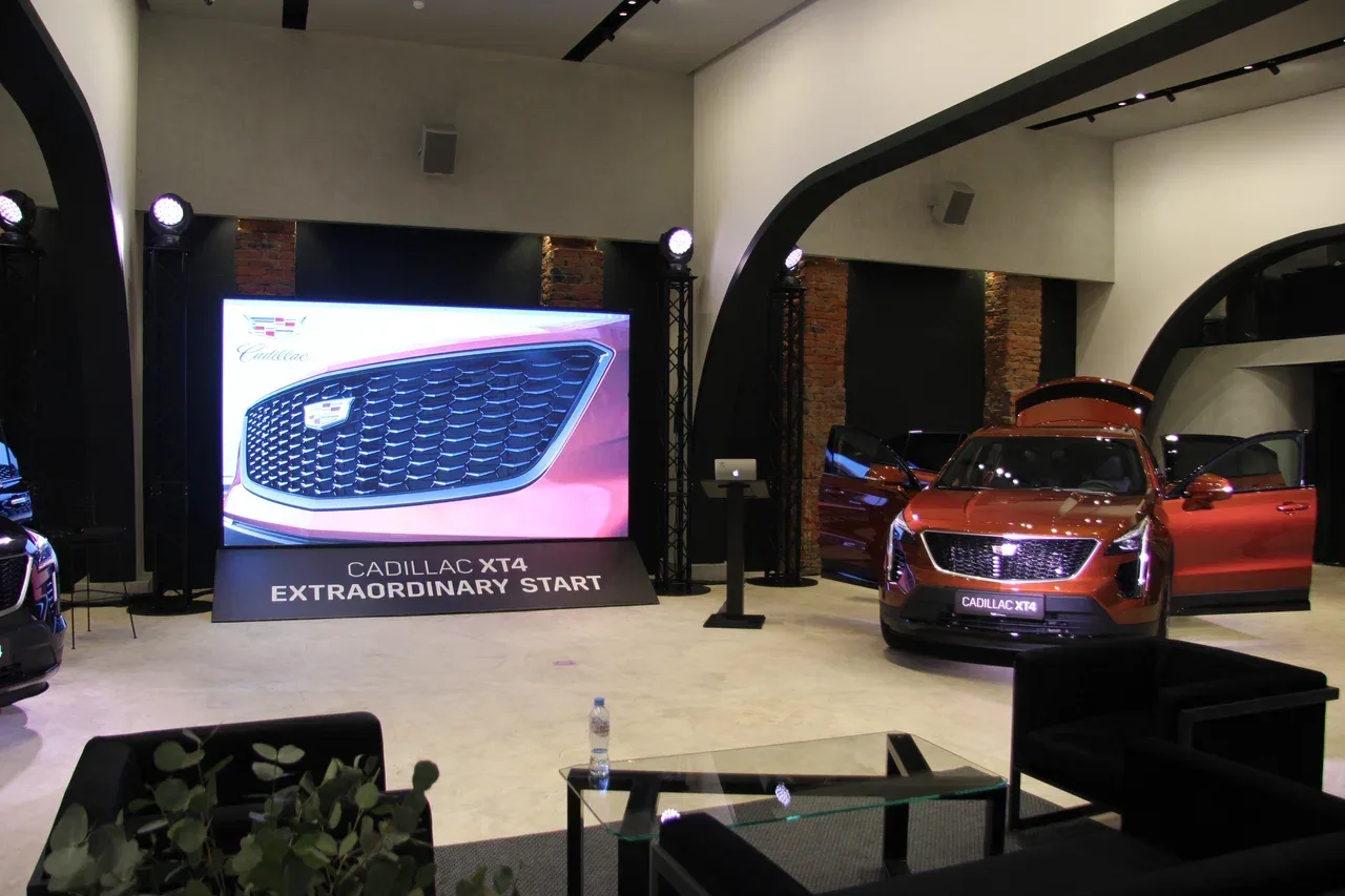 Cadillac XT4 рядом с экраном на презентации в Grey Green
